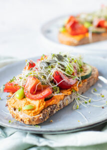 Toast met paprika hummus, gegrilde groenten, sojabonen & pompoenpitten
